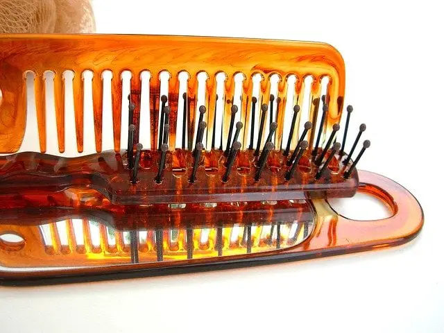 using comb to clean hairbrush bristles